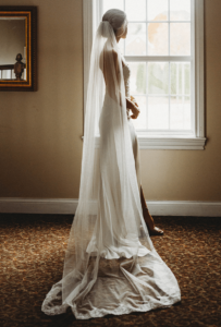 opalona natryskowo panna młoda stoi w sukni ślubnej